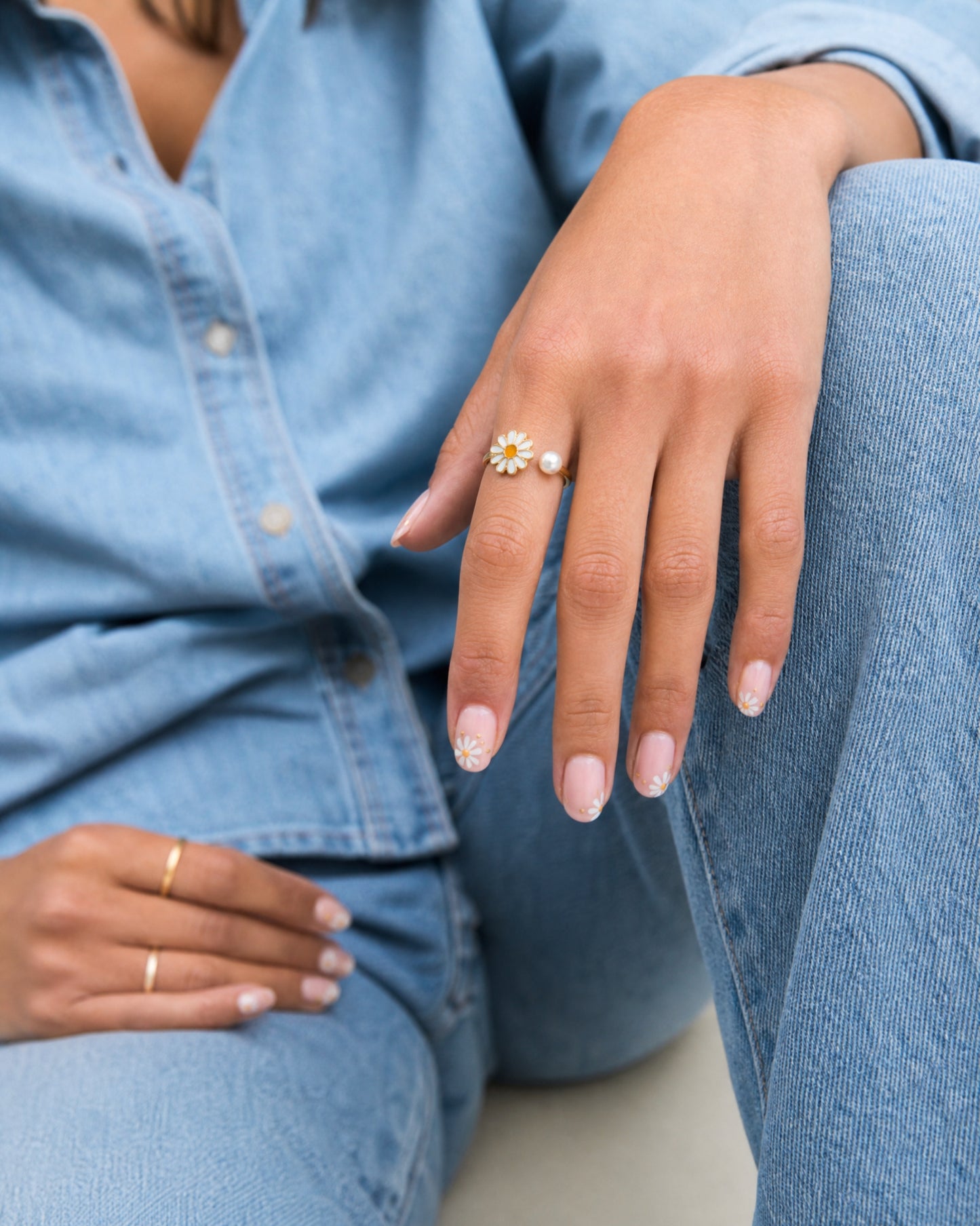 Person wearing a daisy ring with a denim background